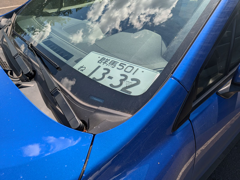 A license plate hastily 'installed' on a dashboard.